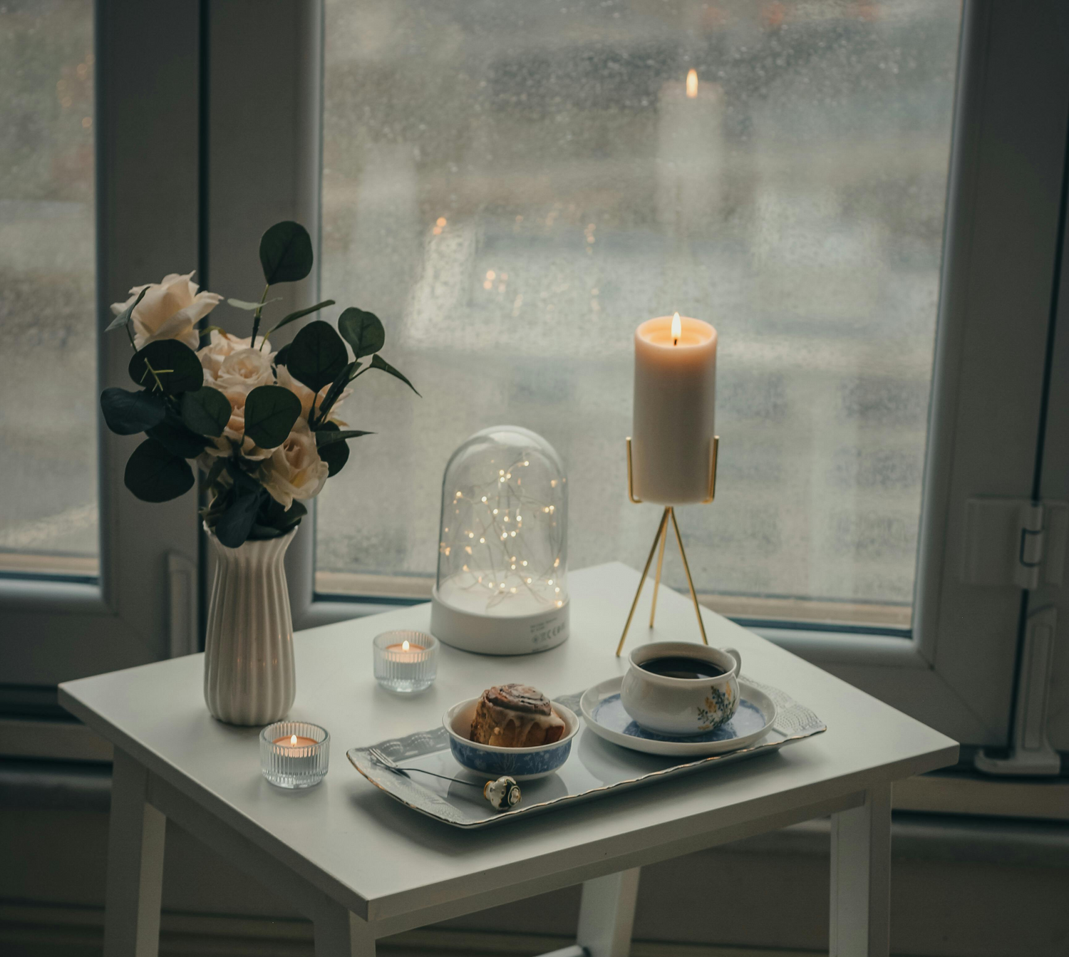 cozy table with coffee, candle near window